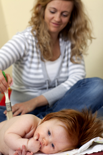 Foto: Mutter streichelt ihre kleine Tochter mit einem Pinsel.